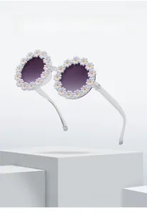 Macro shot of daisy floral sunglasses with clear frames and purple lenses on white stand
