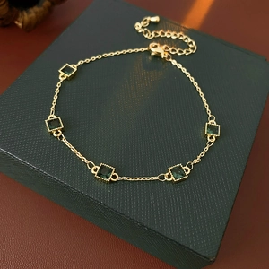 Détail du bracelet plaqué or avec cinq zircons verts carrés sur un coffret à bijoux