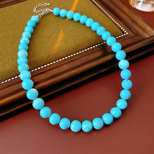 Close-up of a minimalist turquoise beaded necklace with silver clasp on a vintage frame