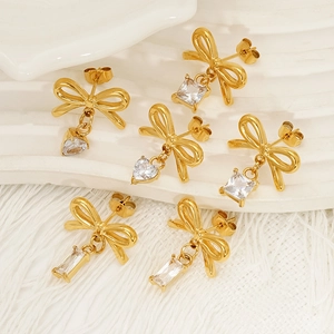 Boucles d'oreilles nœuds dorées avec pendentifs en zircon cœur et carrés sur fond blanc