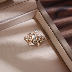 Élégante broche couronne dorée sertie de strass présentée dans un écrin de luxe