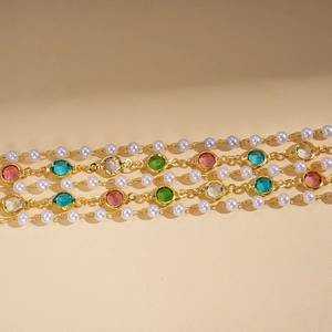Detailed close-up of layered gold necklace with colorful crystals and white imitation pearls