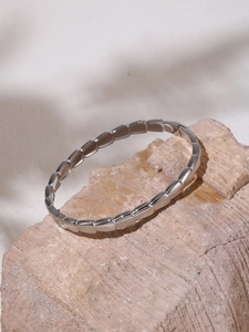 Detailed view of a geometric silver bracelet with rectangular links on a stone base