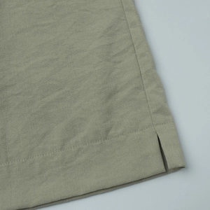 Detailed view of the sage green cotton-linen fabric with a side slit and neat stitching