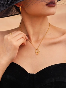 Close-up of a model wearing a hollow twisted gold heart necklace with matching earrings