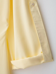 Dettaglio della manica regolabile con bottone bianco sull'abito camicia giallo chiaro