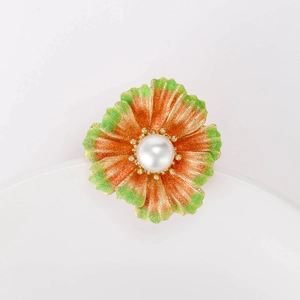 Detailed view of an orange and green gradient flower brooch with a central white pearl