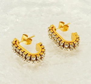 Detailed macro view of C-shaped gold stud earrings with double row sparkling rhinestones