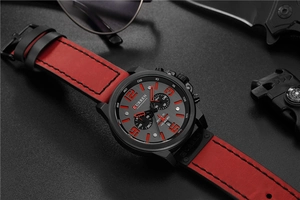 Detail of military style quartz chronograph with red leather strap and black textured dial