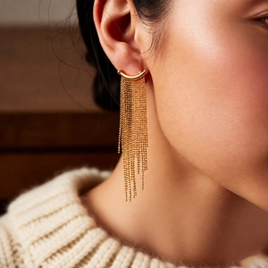 Close-up of elegant gold tassel earrings with multiple metal bead chains worn by a model