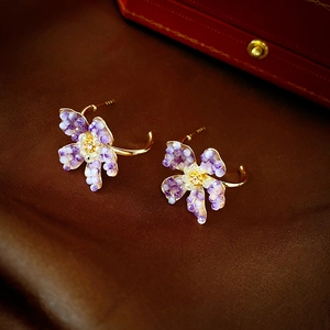 Close-up of purple crystal flower earrings with gold hooks on dark silk fabric