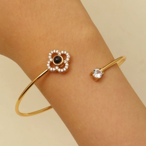 Détail du bracelet trèfle doré avec pierre de projection et incrustation de diamants au poignet