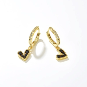 Detailed macro view of gold hoop earrings with heart charms and black cubic zirconia stones