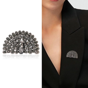 Elegant peacock brooch with grey crystals on a black suit and white background