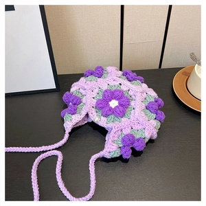 Detail of handmade purple crochet floral earflap hat with thick wool knit texture