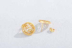 Detailed macro view of gold-plated stainless steel hollow floral stud earrings on white surface