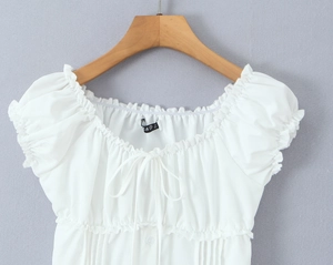Close-up of white puff sleeve blouse featuring puff sleeves and ruffled lace-up neckline