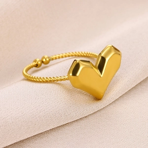 Detail of gold heart ring with twisted band and adjustable open design on fabric