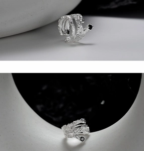 Macro detail of silver ear cuff featuring irregular lava texture and black gemstone