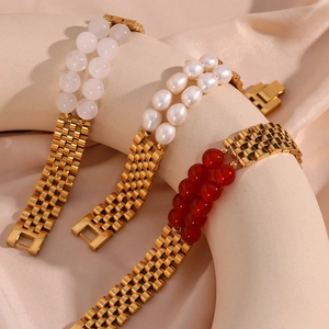 Detailed shot of gold link bracelets with natural stones and pearls on silk background