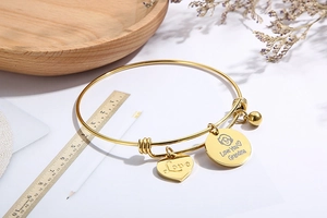 Detail showing Love You Grandma heart and round charms on a golden wire bracelet