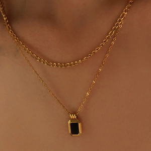 Close-up of double-layered gold necklace featuring a vintage black rectangular pendant