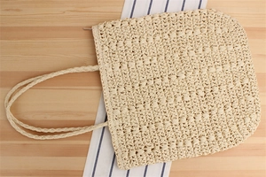 Detail of handwoven paper rope tote bag texture with zipper closure and braided handles