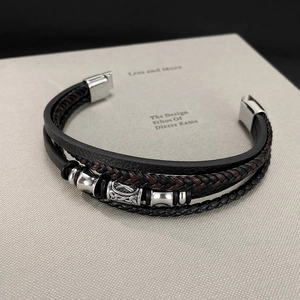 Detail of multi-layer braided leather bracelet with silver metal beads on a book surface