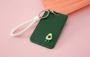 Detail of dark green avocado card holder with white woven wrist strap on pink background