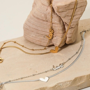Double layer stainless steel anklet with heart and love pendants on beige stone display