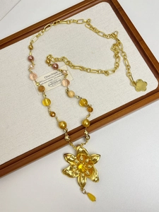 Detail of vintage gold flower pendant necklace with amber beads and pearl accents