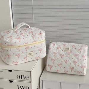 Detail view of quilted floral cosmetic bags with pink bow patterns and carry handles