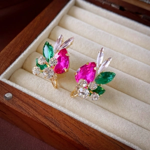 Macro view of crystal teardrop earrings with pink and green stones in a velvet box