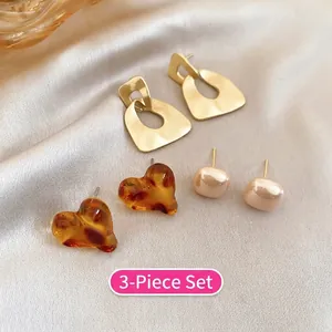 Close-up of a 3-pair vintage earring set with gold geometric, amber heart and beige studs
