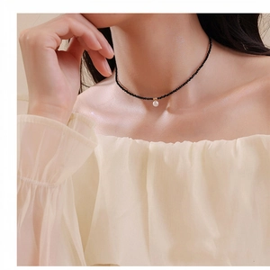 Gros plan sur le choker en perles de cristal noir avec pendentif en perle