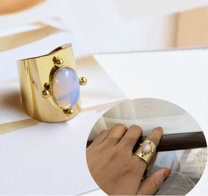 Macro detail of a wide 18K gold plated titanium ring with oval opal and gold beads