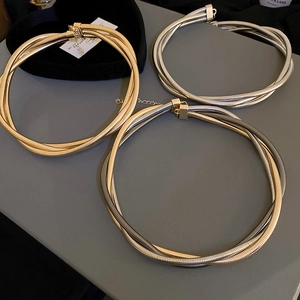 Detailed view of layered multi-strand snake chain necklaces in gold and silver finishes