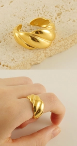 Macro detail of a 18k gold croissant style twisted ring on stone and worn on a finger