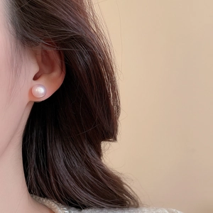 Detail of a 10-12mm round pinkish purple pearl earring worn on the earlobe