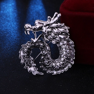Macro detail of silver vintage dragon brooch with textured scales and antique finish