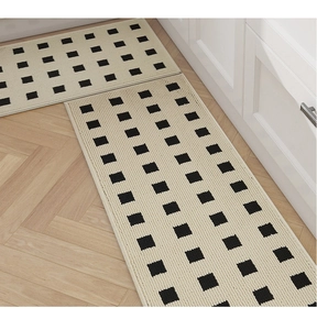 Close-up of beige kitchen mats with black grid pattern on herringbone wood flooring