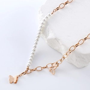 Irregular pearl and gold chain necklace with butterfly pendants on a stone base