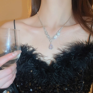 Close-up of sparkling pear-cut zircon pendant necklace worn with elegant black feather top