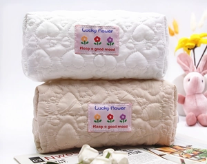 Detailed view of quilted heart pattern and embroidered lucky flower label on soft pouches