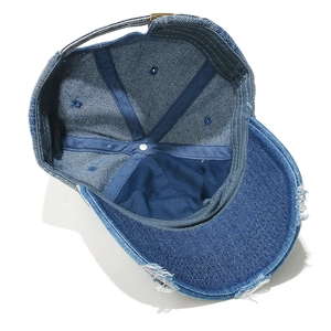 Detail view of denim baseball cap with distressed brim and metal adjustable buckle