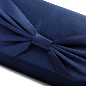 Close-up of a navy blue satin clutch bag showing the elegant silk bow knot detail