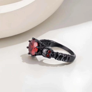 Macro detail of gothic black skull ring with a large faceted red gemstone and carvings