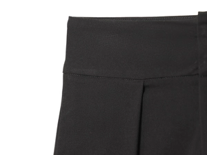 Detail view of high waist pleated balloon trousers in black with smooth fabric texture