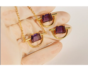 Macro shot of gold-plated pendant set with purple trapezoidal gemstone for scale