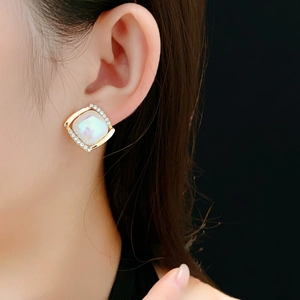 Gros plan de boucles d'oreilles carrées en or avec nacre irisante et zircons brillants